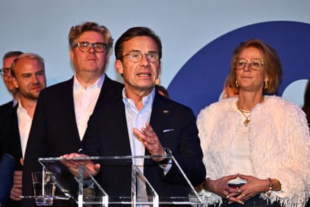 Sweden’s prime minister, Ulf Kristersson, standing at a podium in front of three men and a woman