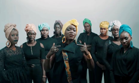 Sister LB stands flanked by eight other women stood behind her, all dressed in black, with varied colourful headscarves in the video for her song Maa La Dig Tekki.