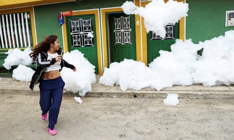 A woman moves away from the foam by her house in Mosquera. Authorities have warned locals against getting too close to the foam.