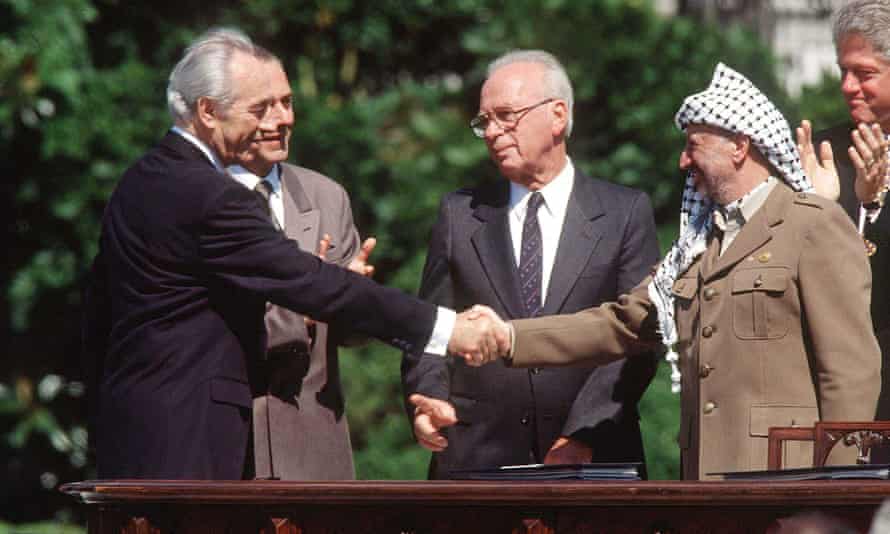 Yitzhak Rabin shaking hands with Palestinian leader Yasser Arafat at the White House in a deal brokered by Peres.