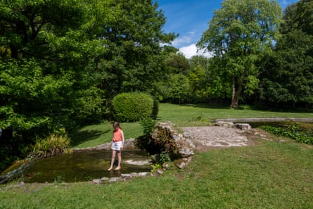 A child stands in a water feature in the estate grounds