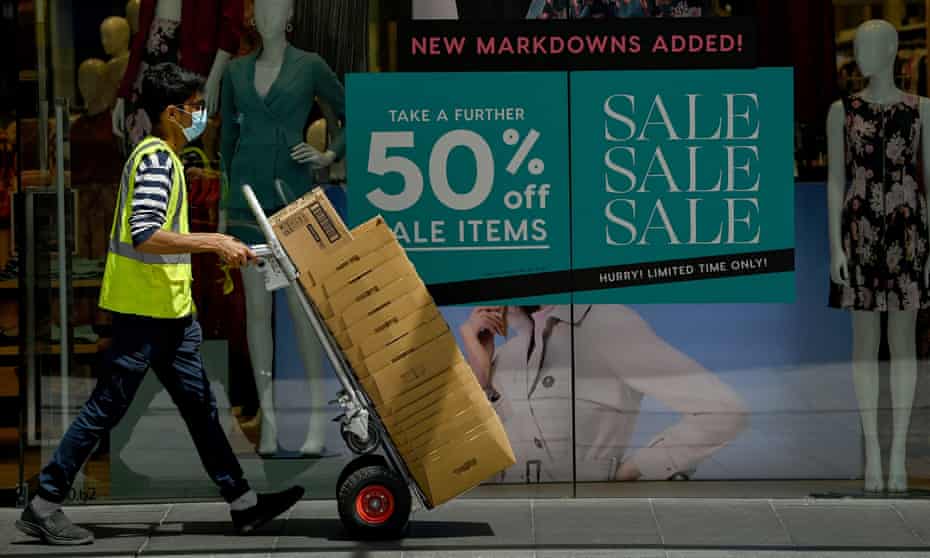 A courier worker walks past retail signage on a shopfront in Sydney