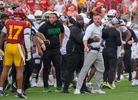 Oregon Ducks head coach Dan Lanning is held back by staff after the late hit on Dante Moore