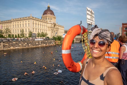 Lina Lahiri in a swimsuit smiles next to the Spree River in Berlin