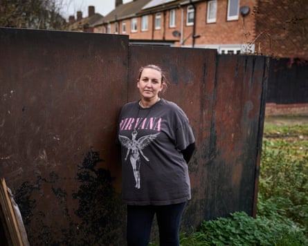 Serenity Colley, a resident on the Nunsthorpe estate, stands next to the metal wall dividing her house from neighbours in the newer, bigger properties at Scartho.