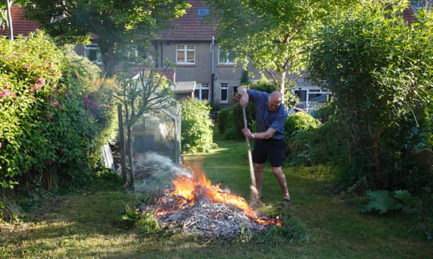 A man tends to a bonfire in a Devon garden.
