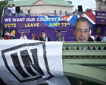 People drape a banner over a bridge reading 'IN