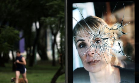 Anuncio exterior con la imagen de una mujer mirando a través de un panel de vidrio roto