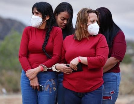 Asylum-seeking migrants stand handcuffed together before being transported to a US Border Patrol processing centre on 29 November in Jacumba Hot Springs, California. The remote community, with a population of 600, has seen a recent influx of hundreds of asylum seeking migrants arriving daily and sheltering in makeshift camps in the desert cold