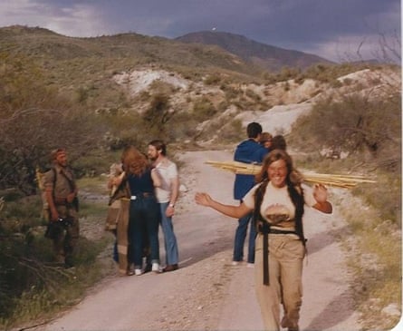 A woman excitedly waves while standing next to a group of people chatting on a wildnerness trail