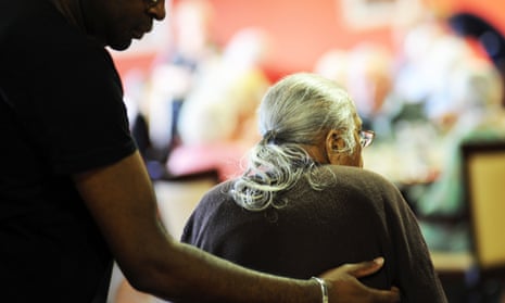 An elderly Sikh lady is helped to her chair in a multicultural extra Care home Bradford West Yorkshire.
