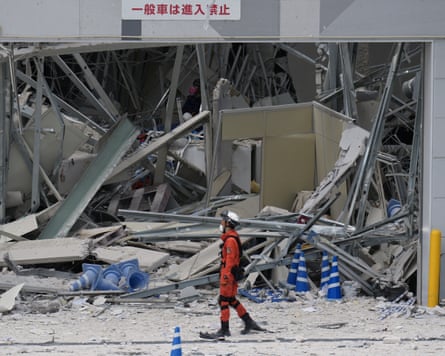 A rescue worker walks in front of a badly damaged building