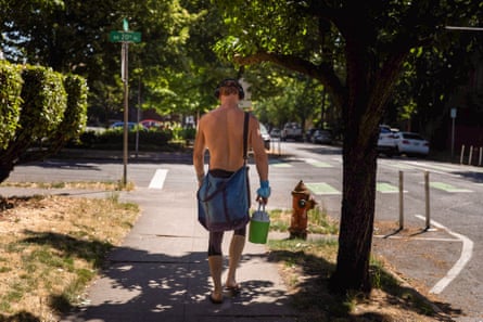 Um homem carregando uma jarra de água durante a onda de calor de 2021 em Portland, Oregon.