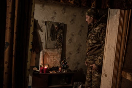 Ukrainian soldier who goes by the name Fox looks at a small Christmas tree sent by his wife, bathed in the soft glow of the Light of Peace, a candle whose flame originated in Bethlehem and was brought by volunteers