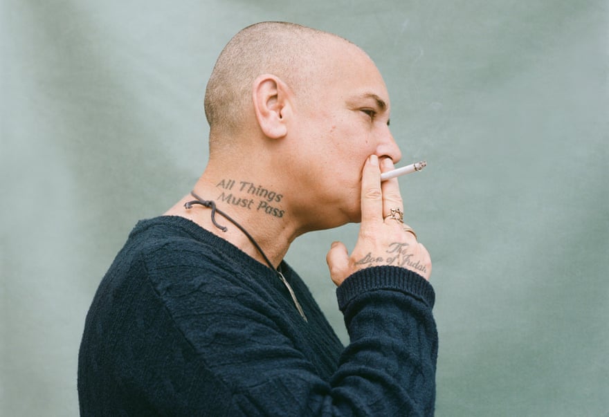 Head shot of Sinead O’Connor, smoking a cigarette, against green background