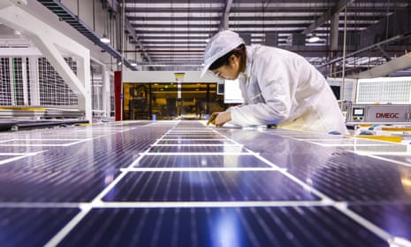 A worker checks a solar PV panel at a manufacturing plant in Jiangsu province, China