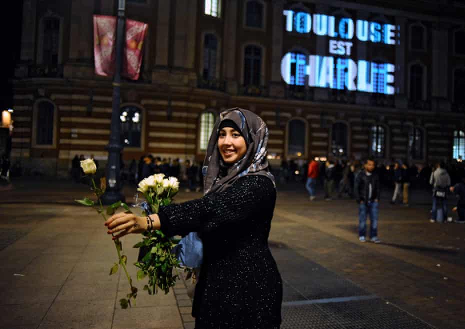 A woman holds out a white rose in Toulouse following the Charlie Hebdo attacks.