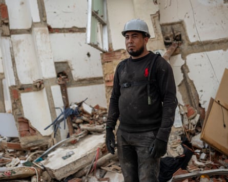 Esnaider Meléndez wearing a white hard hat stood next to a collapsed building