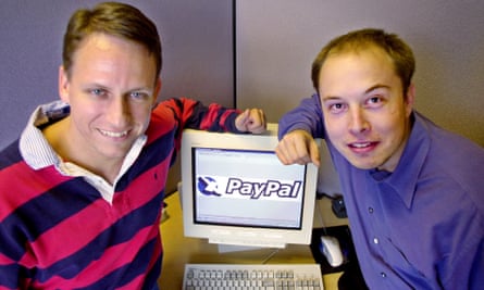 A laptop sits between two men who have their elbows over the screen which reads PayPal.