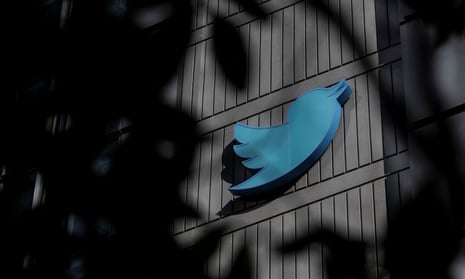 View of twitter sign on outside of a building through silhouetted leaves on a tree