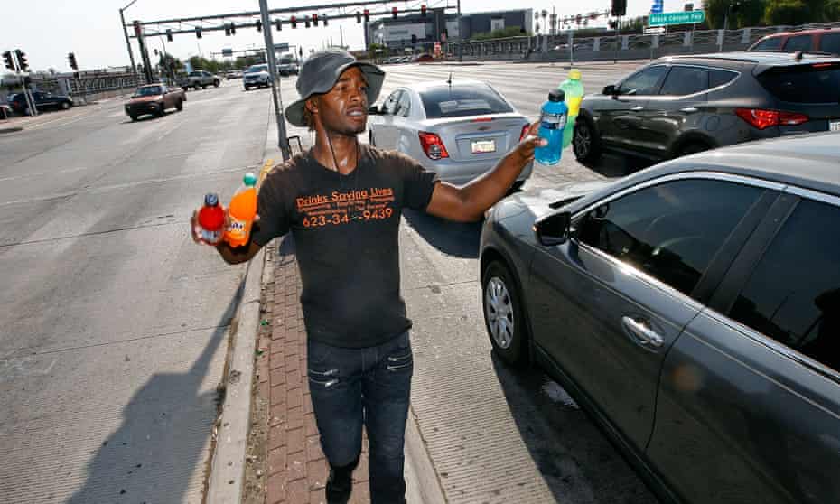 Man sells cold bottled drinks to motorist at a busy intersection on June 20, 2017 in Phoenix, Arizona. 