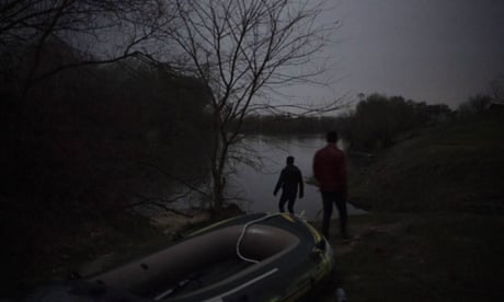 Silhouettes of two men by an inflatable boat next to a river
