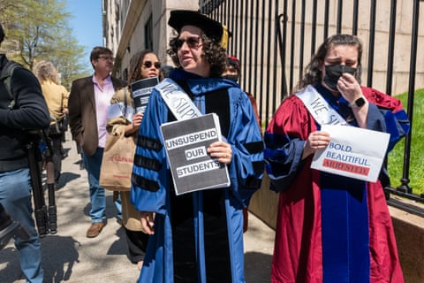 Professors in regalia hold signs, one reading 'unsuspend our students'