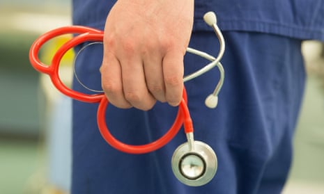 A doctor holds a stethoscope in a hospital ward
