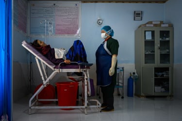 Atifa, wearing PPE, stands in front of a pregnant woman in labour at a medical facility