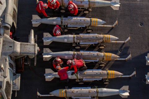 People dressed in red work on silver missiles
