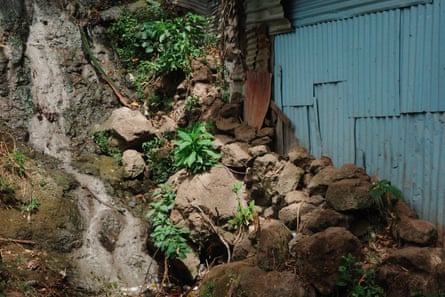 A house built into a rock wall, with rain water running down it