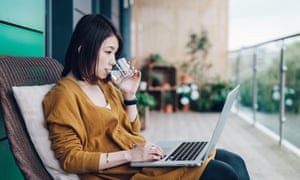 Young woman using laptop and drinking water