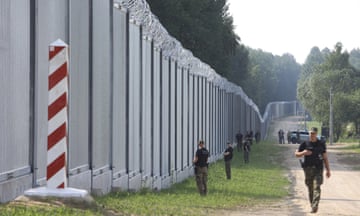 Polish border guards patrol near a metal wall