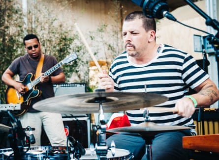 Parker playing guitar, with Herndon holding a drumstick over a cymbal in the foreground