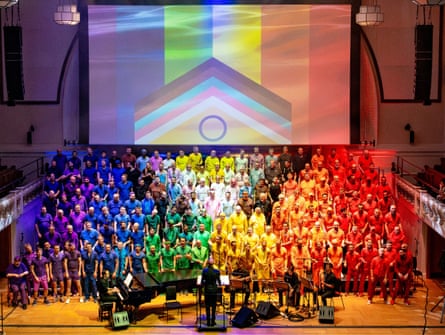 London Gay Man's Chorus performing on stage, wearing T-shirts the colours of the rainbow