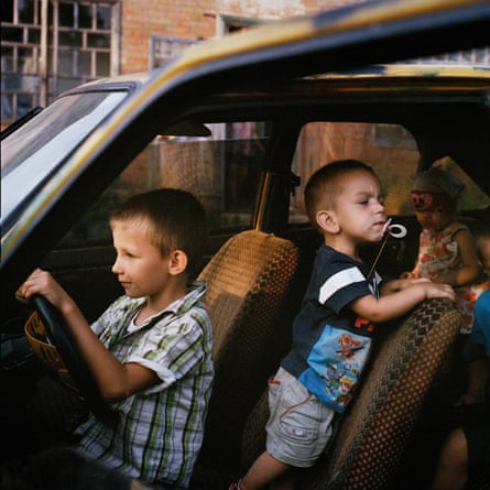 Two small boys playing in a car, one pretending to drive it