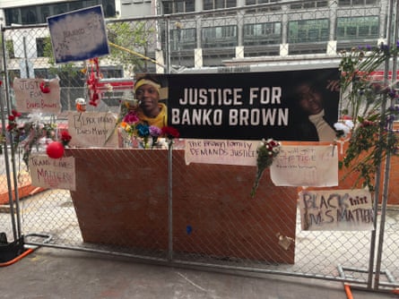 A sign reading ‘Justice for Banko Brown’ is attached to a chain link fence with signs of support around it.