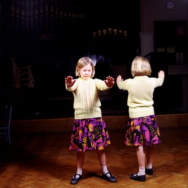 A girl, standing alongside her reversed double, seems to be sleepwalking. She extends her arms and hands, as though encountering an obstacle