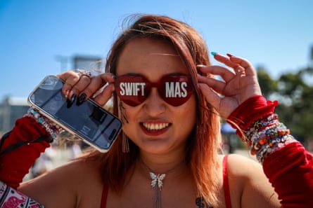 A swiftie poses with ‘Swiftmas’ sunglasses