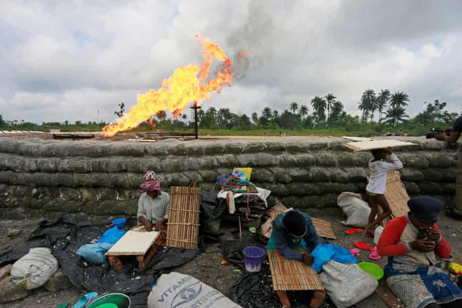 A family prepare tapioca behind sand barriers surrounding a gas flaring furnace at a flow station in Ughelli, Delta StateA family prepare tapioca, which is derived from cassava paste, behind sand barriers surrounding a gas flaring furnace at a flow station in Ughelli, Delta State, Nigeria September 17, 2020. Picture taken September 17, 2020. REUTERS/Afolabi Sotunde