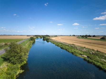 Straight stretch of river in arable farmland on a sunny day