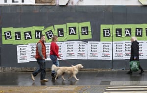 People walk past posters put up by climate activists in Glasgow