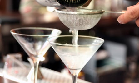 bartender’s hand pours martinis