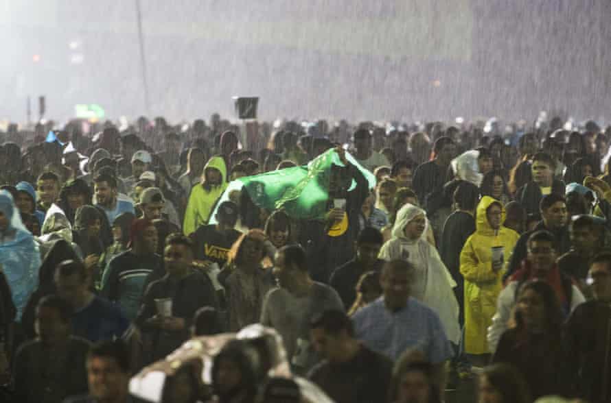 Spectators walk in the rain during the Vive Latino rock music festival in Mexico City on Sunday.