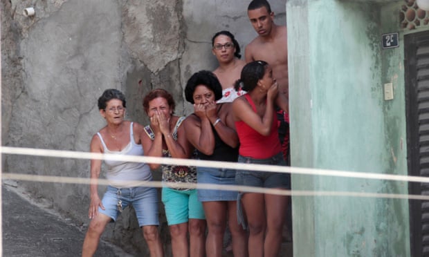 Residents react after a gun battle between police and gang members set a house on fire at the Complexo do Alemao slum in Rio.