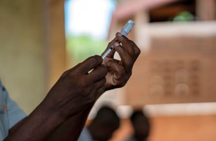 Hands holding a syringe and a vial of vaccine
