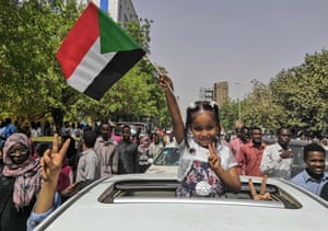 A young girl flashes the victory sign and holds the national flag during a rally near the military headquarters