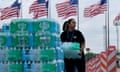 Woman hands out bottled water with American flags in background