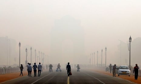 People walk in front of the smog covered India Gate war memorial in Delhi, India.