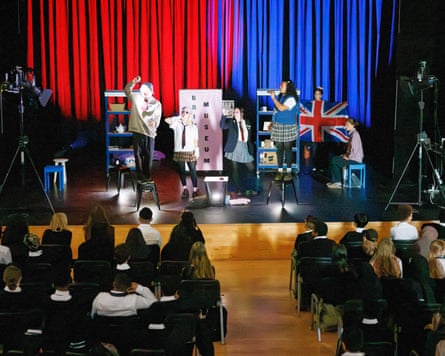 Actors perform A Brit?ish Museum on stage with red and blue curtains and a Union Jack flag